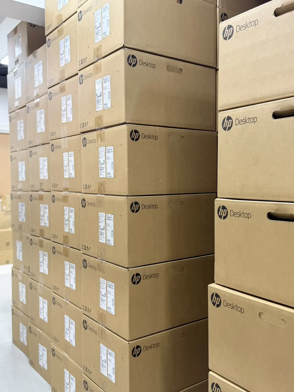 Cartons of HP desktop computers stacked in the Colion International stock room
